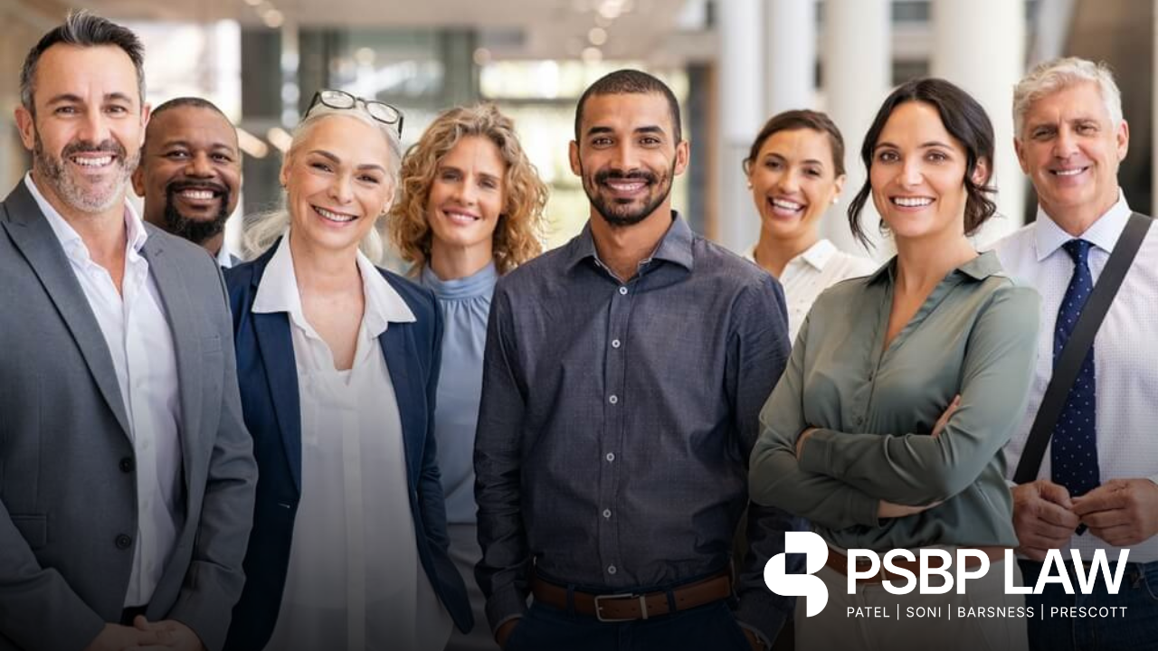 Group of professionals collaborating around a laptop in a modern office, illustrating “What is L-1B Visa,” with PSBP LAW branding in the corner.